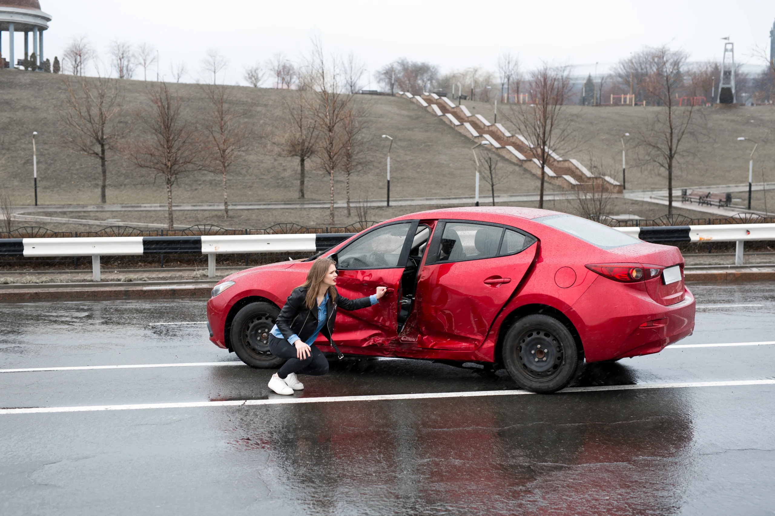 woman sits near a broken car after an accident